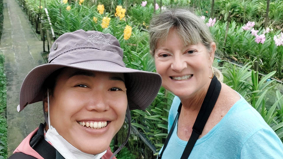Deborah C. with Bangkok tour guide Apple exploring a vibrant orchid garden in Thailand